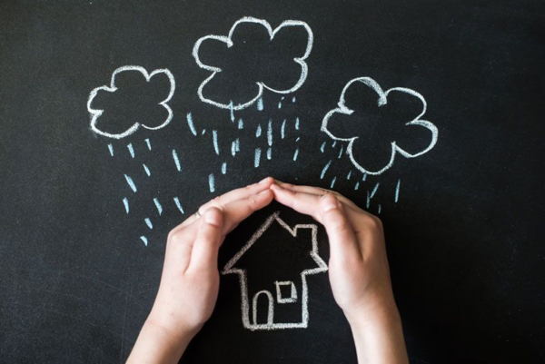 hands shielding a chalk drawing on a home from rain